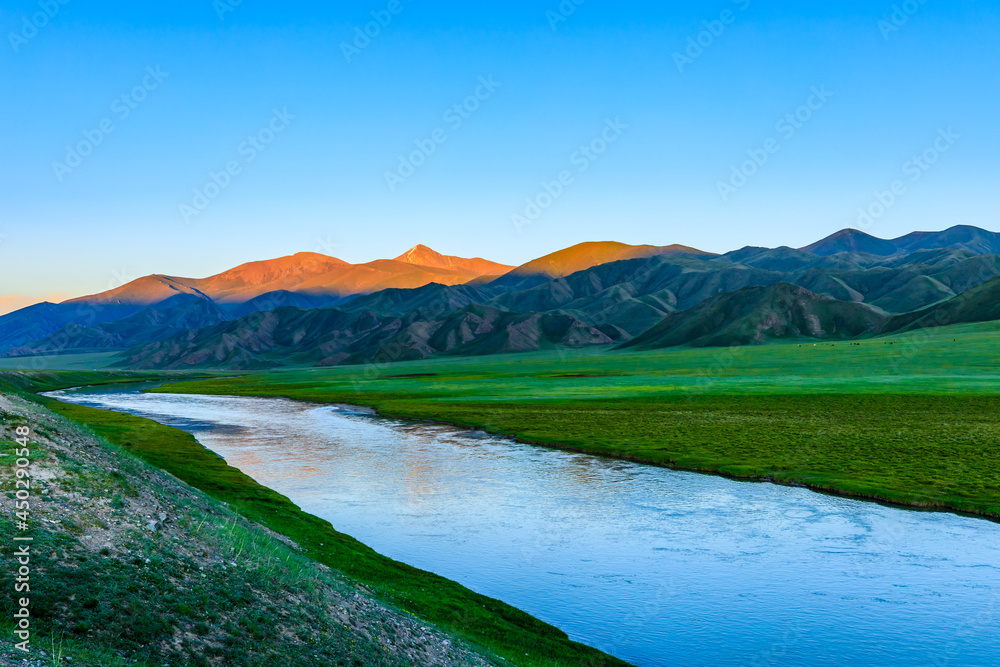 Grassland and river with mountain natural landscape in Xinjiang at sunset.