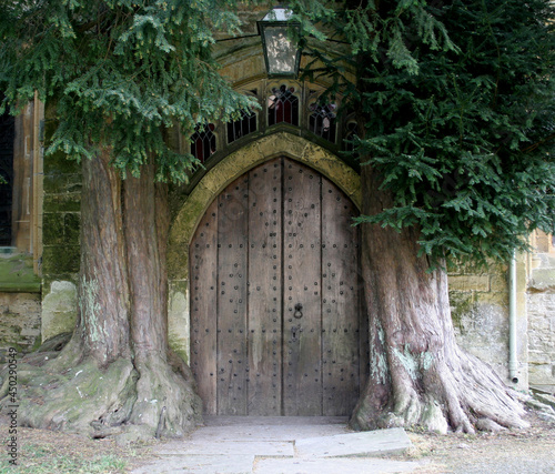 A mysterious door set beside 2 trees on the building of a church in Stow on the Wold in Gloucestershire in the UK photo