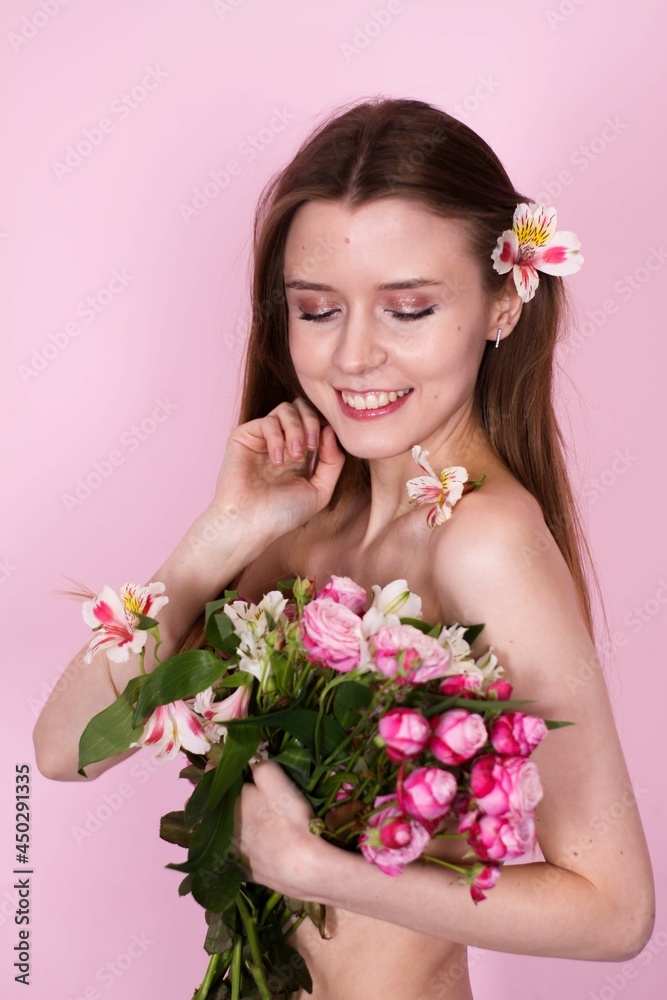 naked skinny girl holding flowers on a pink background. brunette naked skinny girl holding flowers on a pink background. brunette