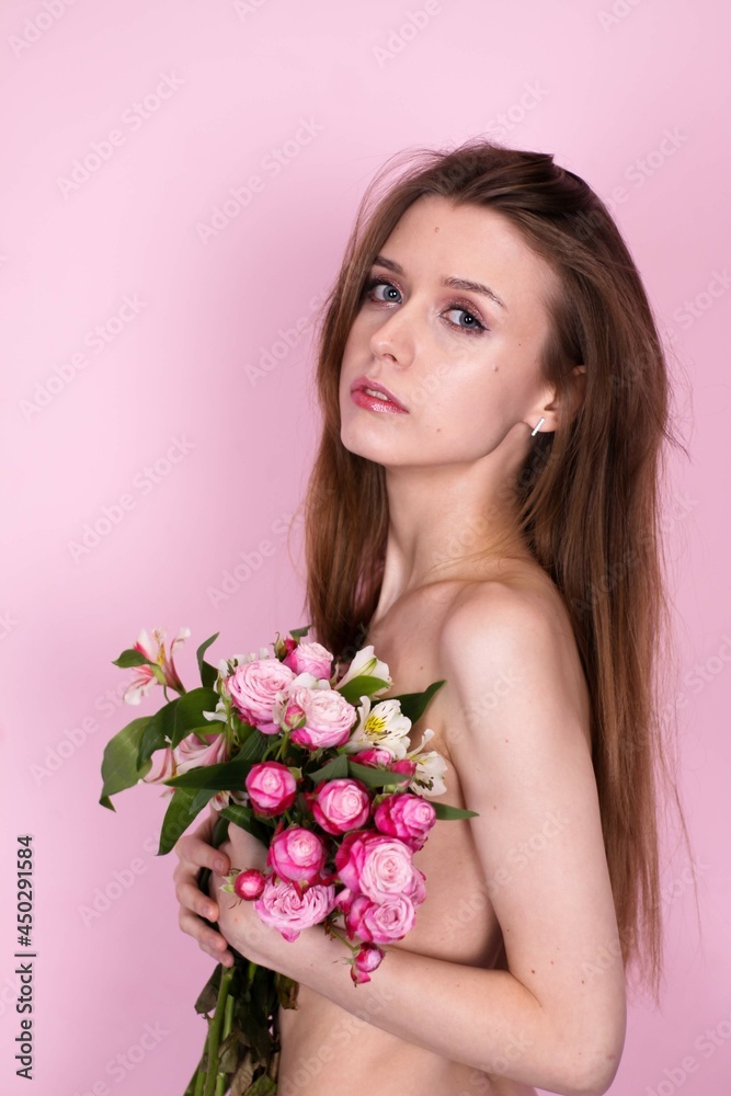 naked skinny girl holding flowers on a pink background. brunette naked skinny girl holding flowers on a pink background. brunette