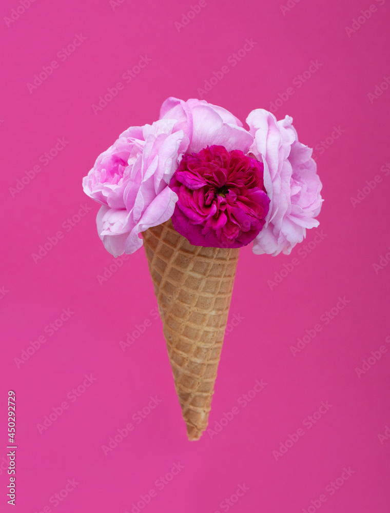 Ice cream waffle cone with a bouquet of summer flowers roses over pink ...