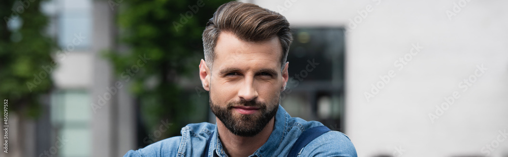 Fototapeta premium Young man looking at camera outdoors, banner