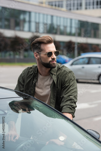 Man in sunglasses looking away near car outdoors