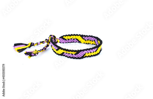 Woven tied DIY friendship bracelet handmade of embroidery bright thread with knots on white background.