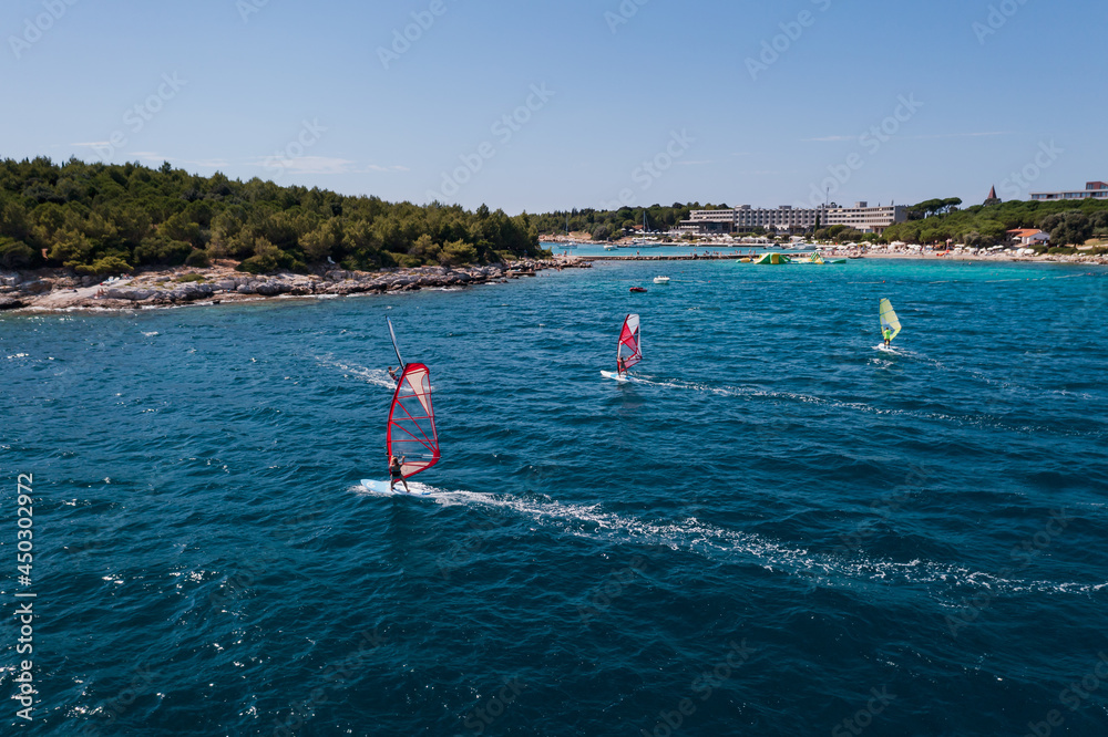 water sports: windsurfers with colored sails in oceanic blue water