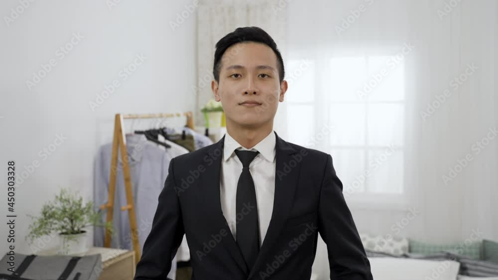 confident asian male wearing business suit and facing camera like mirror is leaving home for work with suitcase after preparing and checking his look in the morning confident asian male wearing business suit and facing camera like mirror is leaving home for work with suitcase after preparing and checking his look in the morning