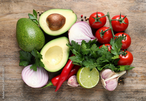 Fresh ingredients for guacamole on wooden table, flat lay