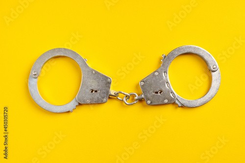 Fotografie, Tablou Handcuffs on yellow background.