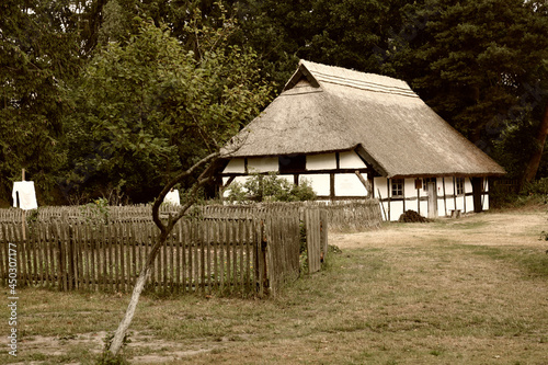 Stara wiejska chata na terenie wiejskim z płotem, przy alejce. photo