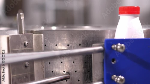 Automatic production, conveyor, ready-filled liquid bottle with a red lid is rotated by the machine.