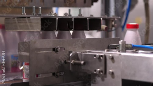 Production of milk or yogurt factory. The wet bottles move along the conveyor belt. Ordering and completing of finished products. Lining up filled plastic bottles with a red lid.