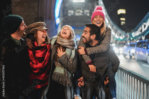 Happy friends having fun walking around the city in winter night - Focus on center girl face