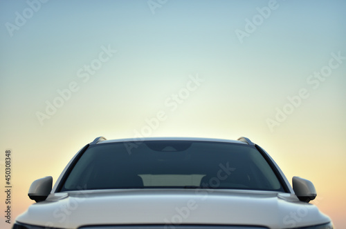 top front part of white parked car against dusk sky