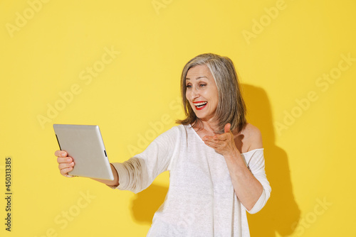 White senior woman gesturing while using tablet computer