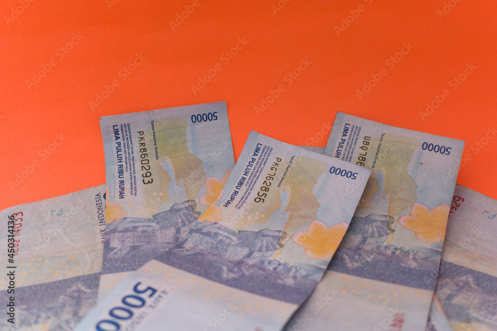 Obraz premium The Indonesian currency is rupiah, which is very much scattered and is worth fifty hundred thousand rupiah. Isolated in orange. For illustrations of news with the theme of economy, buying sell.
