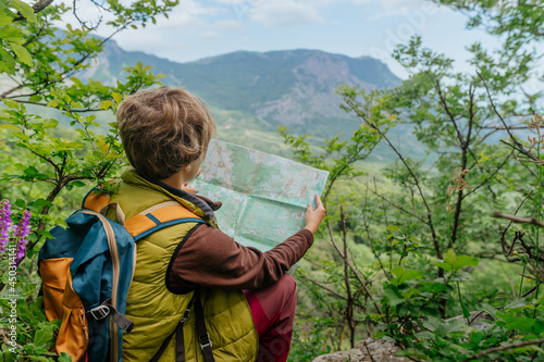 Hiker looking at the map sitting on the cliff