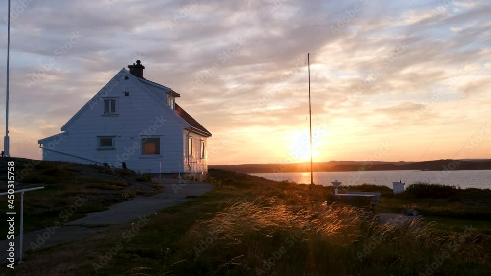 Traditional Waterfront House At The Coast Of Store Torungen Island In Arendal, Norway With Bright Sunlit Background On A Sunset. wide shot Traditional Waterfront House At The Coast Of Store Torungen Island In Arendal, Norway With Bright Sunlit Background On A Sunset. wide shot