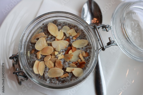 Chia seed pudding with sliced almonds in a glass jar and with a teaspoon