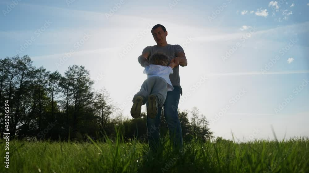 people in the park. happy family a playing in the park in summer. dad keeps whirling son and hands have. happy family kid dream concept. fun dad and son silhouette whirling green park