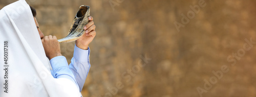 Jewish man in tallit blowing shofar outdoors, banner design. Rosh Hashanah celebration