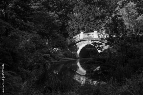 Static view of Parc Monceau with beautiful stone bride across river on summer day in Paris, France. black and white photo
