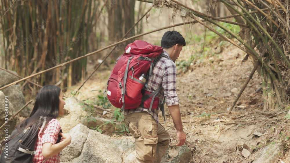 A group of young Asians are planning and looking at maps for camping in the forest.Asian and caucasian are backpackers.Tourism, adventure and summer vacation concept A group of young Asians are planning and looking at maps for camping in the forest.Asian and caucasian are backpackers.Tourism, adventure and summer vacation concept