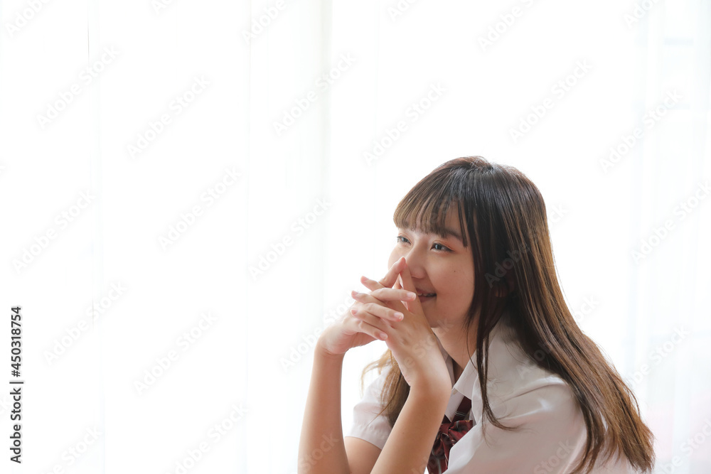 Portrait japanese school girl uniform sitting and look at camera in white tone bed room Portrait japanese school girl uniform sitting and look at camera in white tone bed room
