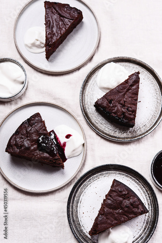 Slices of rich moist chocolate cherry cake. Homemade dark chocolate sweet brownies cakes with ice cream on greige linen tablecloth. Selective focus