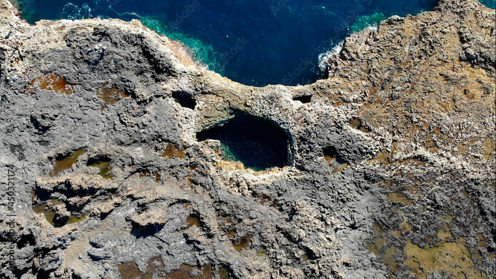Coastal vulcanic blowhole complex with deep blue turquoise sea water seen from far above.
