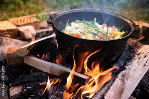 Dutch oven cooking on a campfire with open lid and stew