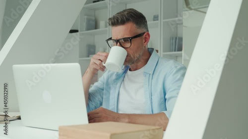 Confident mature man working on laptop while sitting at the office desk