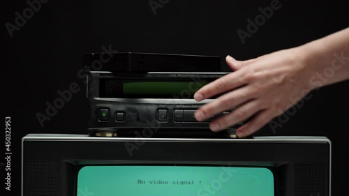 Putting video cassette into recorder. Old retro television with blue screen on black background. Old-fashioned TV, tv setting concept, ripples and interference, searching channel.  photo