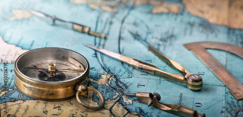 An old geographic map with navigational tools: compass, divider, ruler, protractor. View of the workplace of ship's captain. Travel, geography, navigation, tourism and exploration concept background. photo