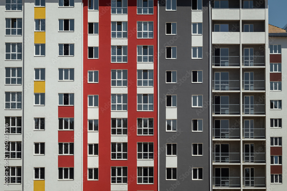 facade wall with multicolored windows of an apartment building on a sunny day in summer