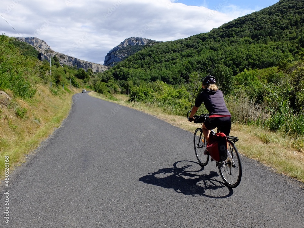 jeune femme à vélo qui randonne en itinérant à bicyclette dans le sud de la France