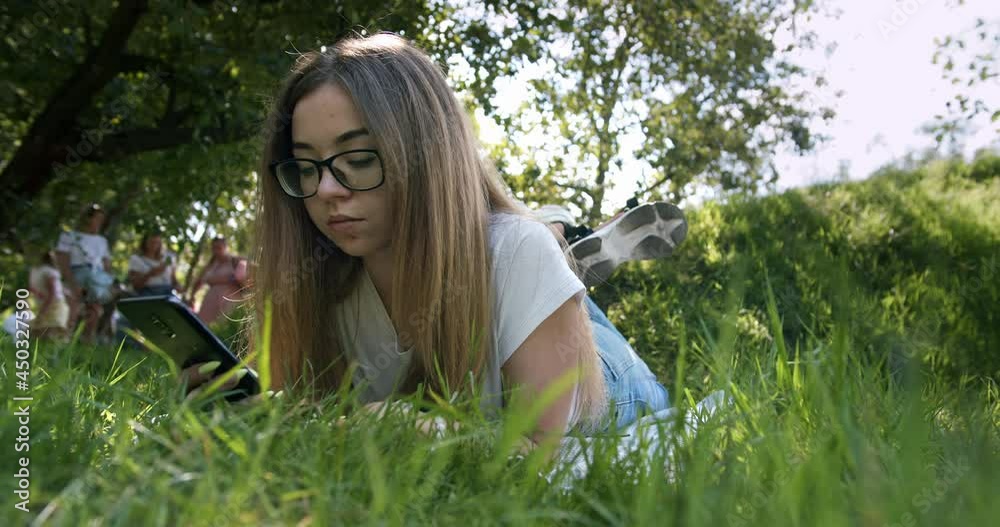 Cute teen girl, student in glasses using smartphone in beauty spring, summer park. Teenager surfing, browsing social media content, using app. Watch content. Cute teen girl, student in glasses using smartphone in beauty spring, summer park. Teenager surfing, browsing social media content, using app. Watch content.