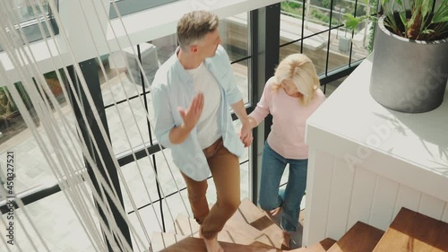 Beautiful mature couple examining new house while walking up by stairs together