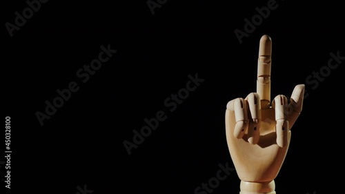 Wooden hand shows obscene gesture with middle finger on black background photo