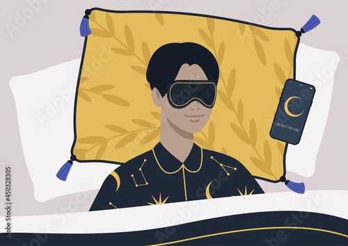 A young male character wearing a night mask and silk pajamas in bed, a mobile phone on silent mode next to them on a pillow