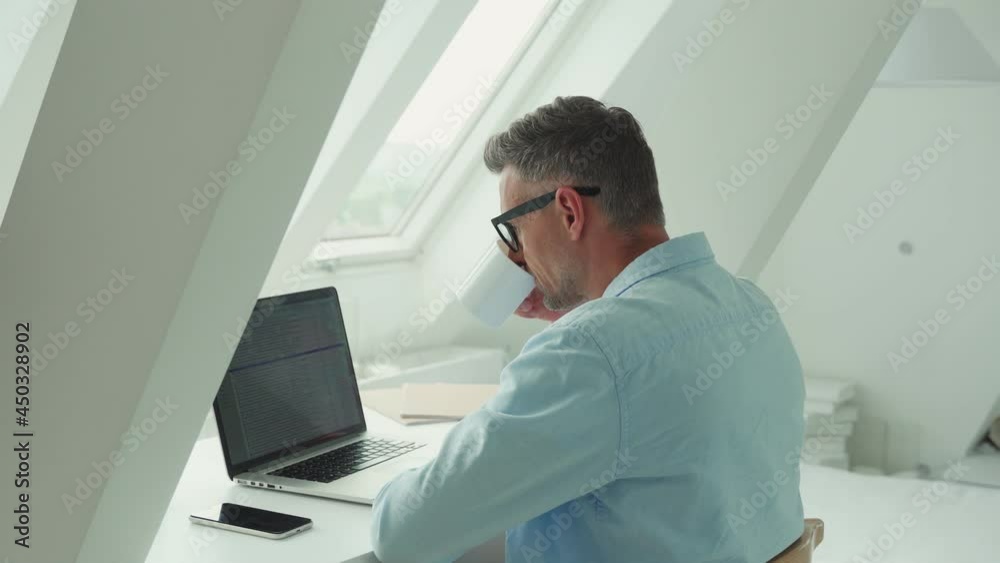 Confident mature man working on laptop while sitting at the office desk Confident mature man working on laptop while sitting at the office desk
