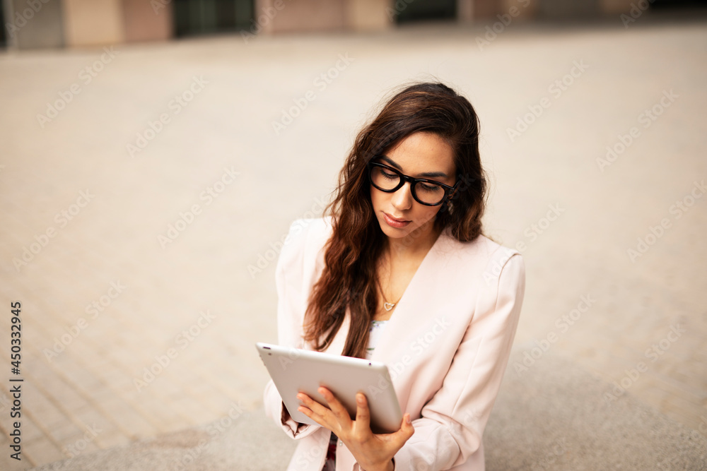 Young businesswoman using tablet outdoors. Beautiful young woman drinking coffee