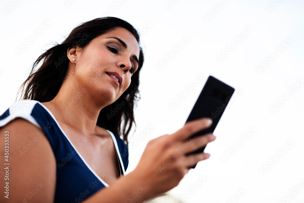 Beautiful young woman using the phone at the beach. Smiling happy woman talking to the phone while resting at the beach Beautiful young woman using the phone at the beach. Smiling happy woman talking to the phone while resting at the beach