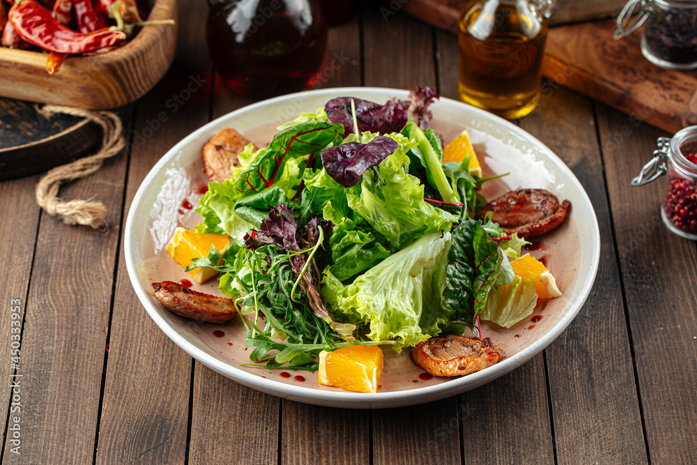 Salad with roasted duck greens and oranges mix on a wooden background