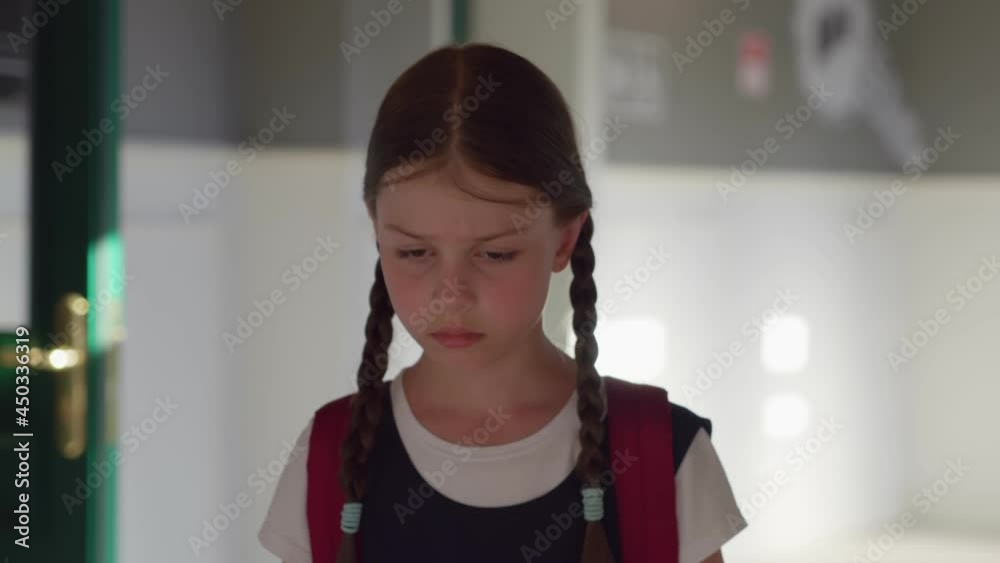 Slider shot of cute upset preteen girl with backpack walking in empty school corridor Slider shot of cute upset preteen girl with backpack walking in empty school corridor