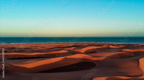 Sand dunes sunset with a wide view of the sea and the horizon.