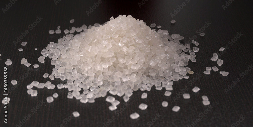 Sugar in glass bowl on wooden background.