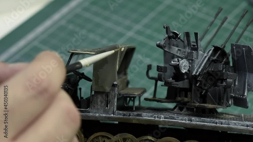 Scale Modeling. A man making Weathering on 1:35 plastic model of German 8ton Semi Track with 20mm flakvierling . Close up. 