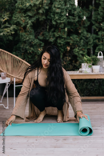 Young adult Filipino woman practicing yoga outside at home