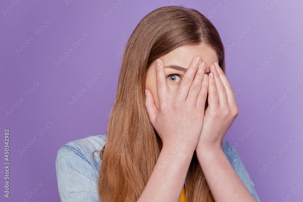 Portrait of frightened lady palm cover face peek eye wear jeans clothes on purple background Portrait of frightened lady palm cover face peek eye wear jeans clothes on purple background