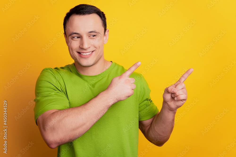 Portrait of curious promoting guy show finger blank space look side on yellow background Portrait of curious promoting guy show finger blank space look side on yellow background